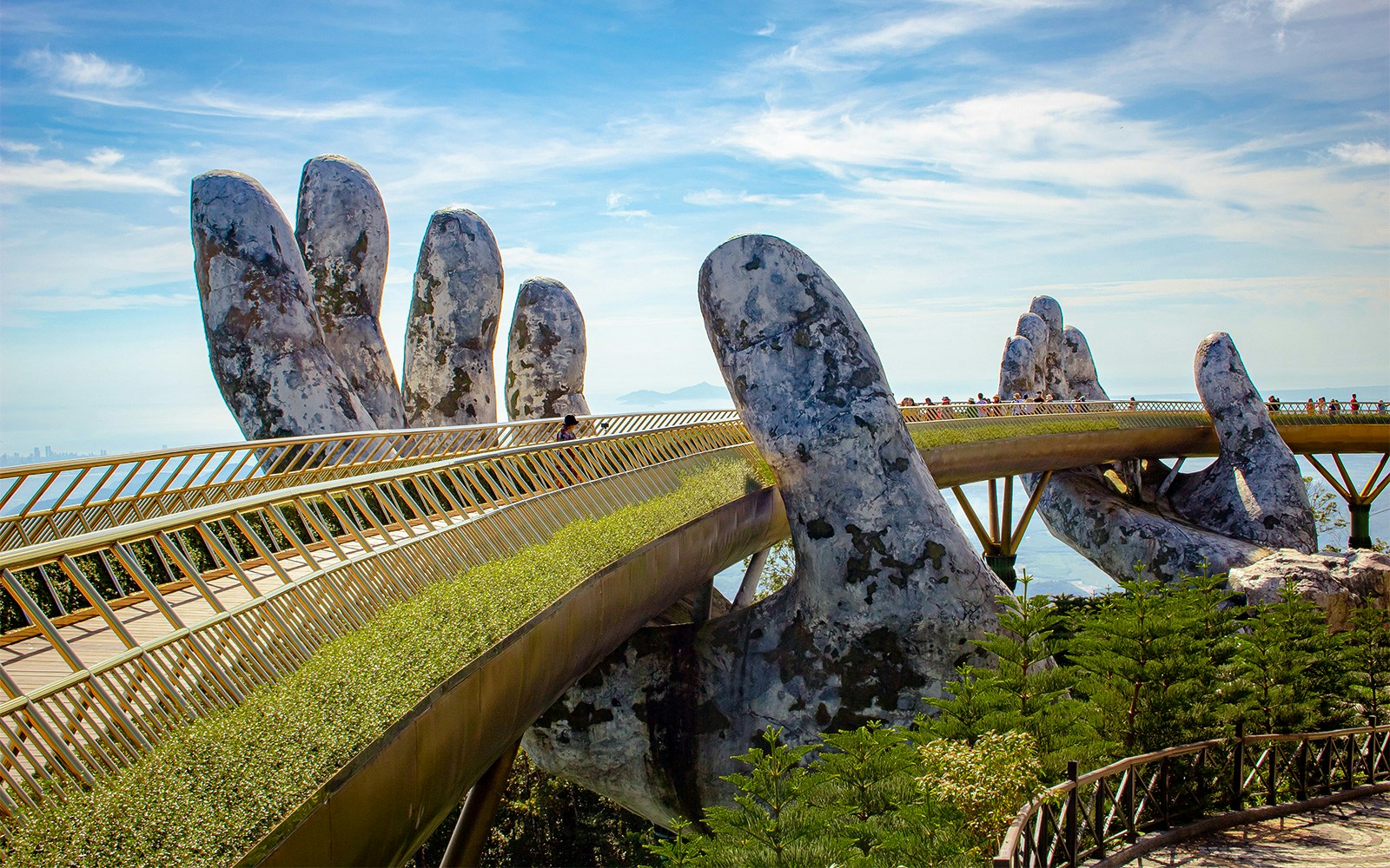 Golden Bridge in Ba Na Hills, Vietnam, with tourists walking across the iconic hand-supported structure.