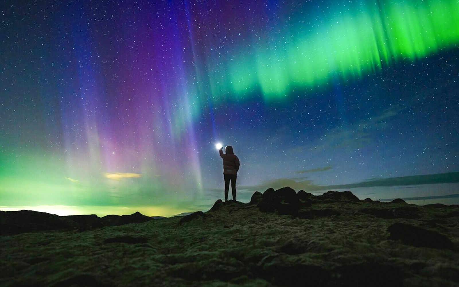 Northern lights over rocky landscape during Premium Northern Lights Super Jeep Tour.