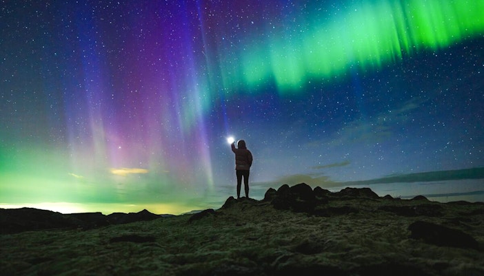 Northern lights over rocky landscape during Premium Northern Lights Super Jeep Tour.