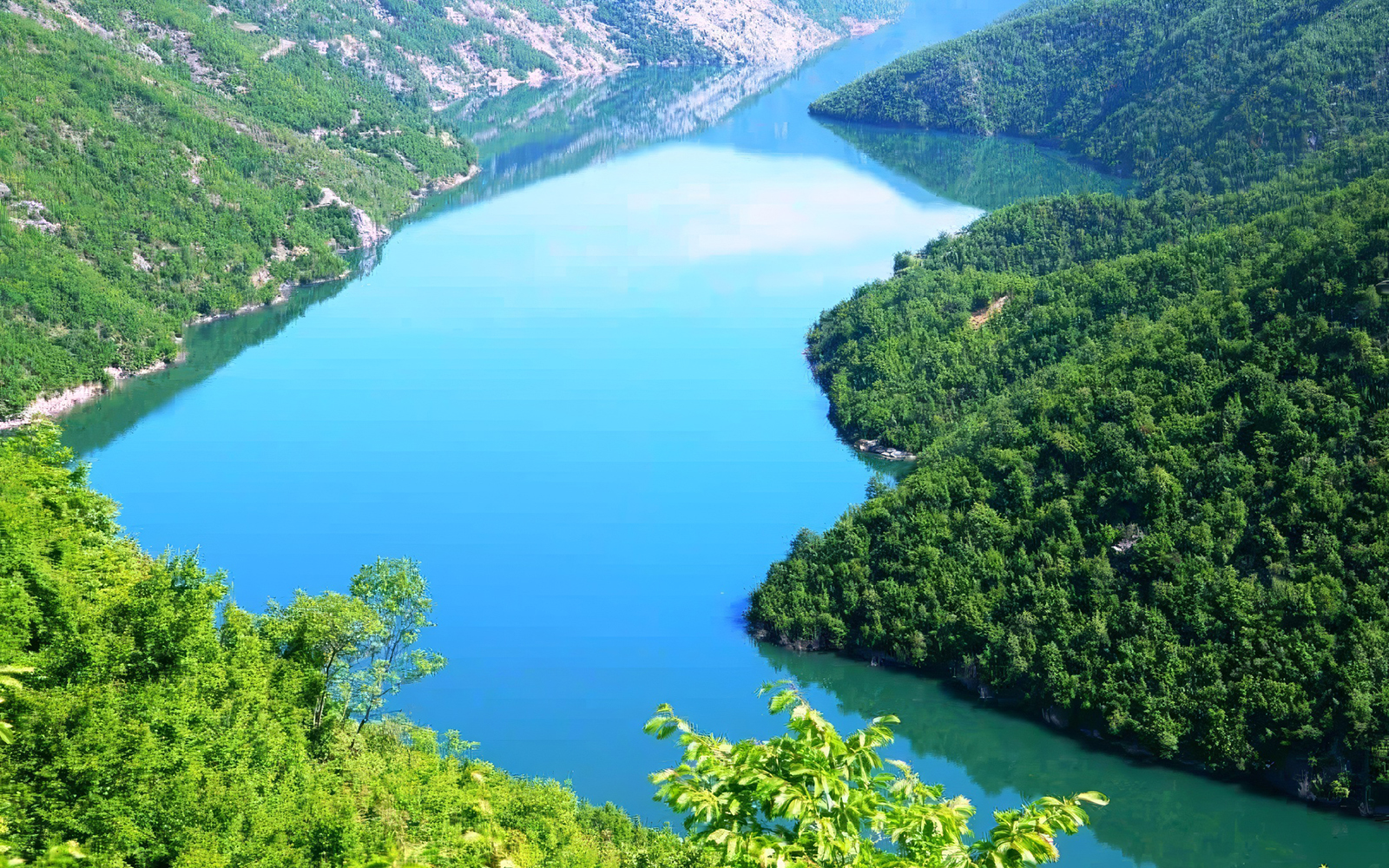 Komani Lake surrounded by lush green hills in Albania.