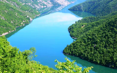 Komani Lake surrounded by lush green hills in Albania.