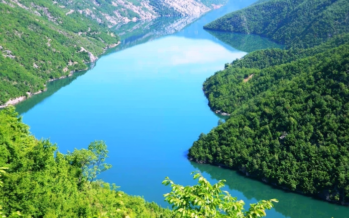 Komani Lake surrounded by lush green hills in Albania.