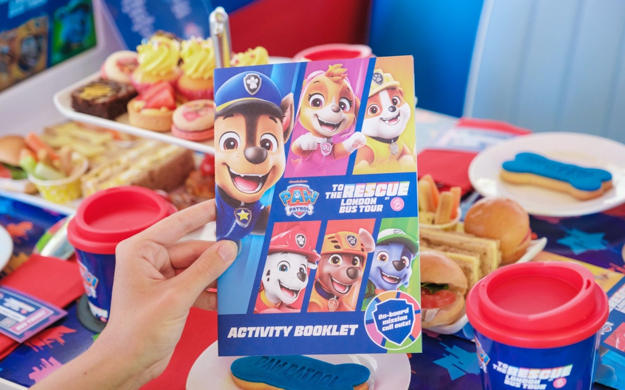 Paw Patrol activity booklet on Brigit’s Afternoon Tea Bus Tour table with themed snacks.