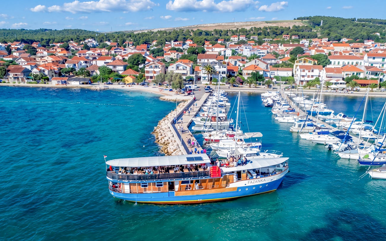 Boat Franzka departing from Zadar, Croatia, with marina and coastal town in background.