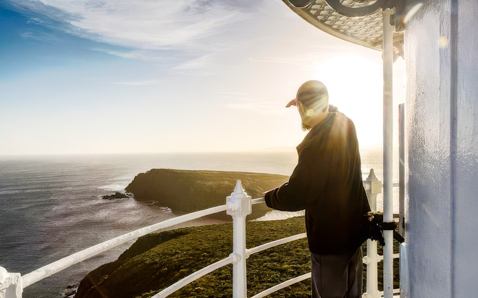 Man viewing ocean from Bruny Island Lighthouse at sunset.
