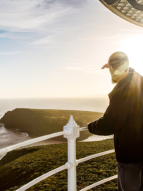 Man viewing ocean from Bruny Island Lighthouse at sunset.