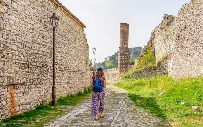 Guest walking along stone path inside Berat Castle, Albania.