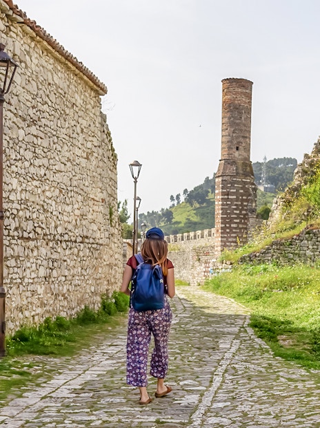 Guest walking along stone path inside Berat Castle, Albania.