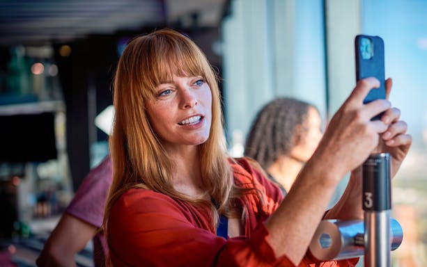 Visitor taking a photo at Melbourne Skydeck with city view in background.