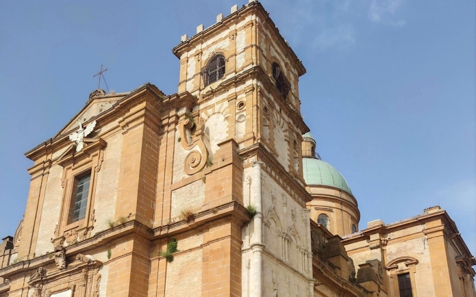 Piazza Armerina Cathedral facade with bell tower and dome under clear sky.
