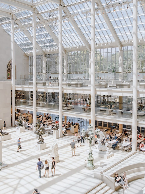 Metropolitan Museum of Art skylit atrium with visitors and sculptures.