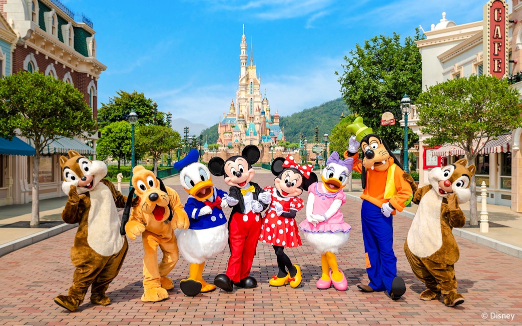 Disney characters on Main Street with castle in background, Disneyland Hong Kong.