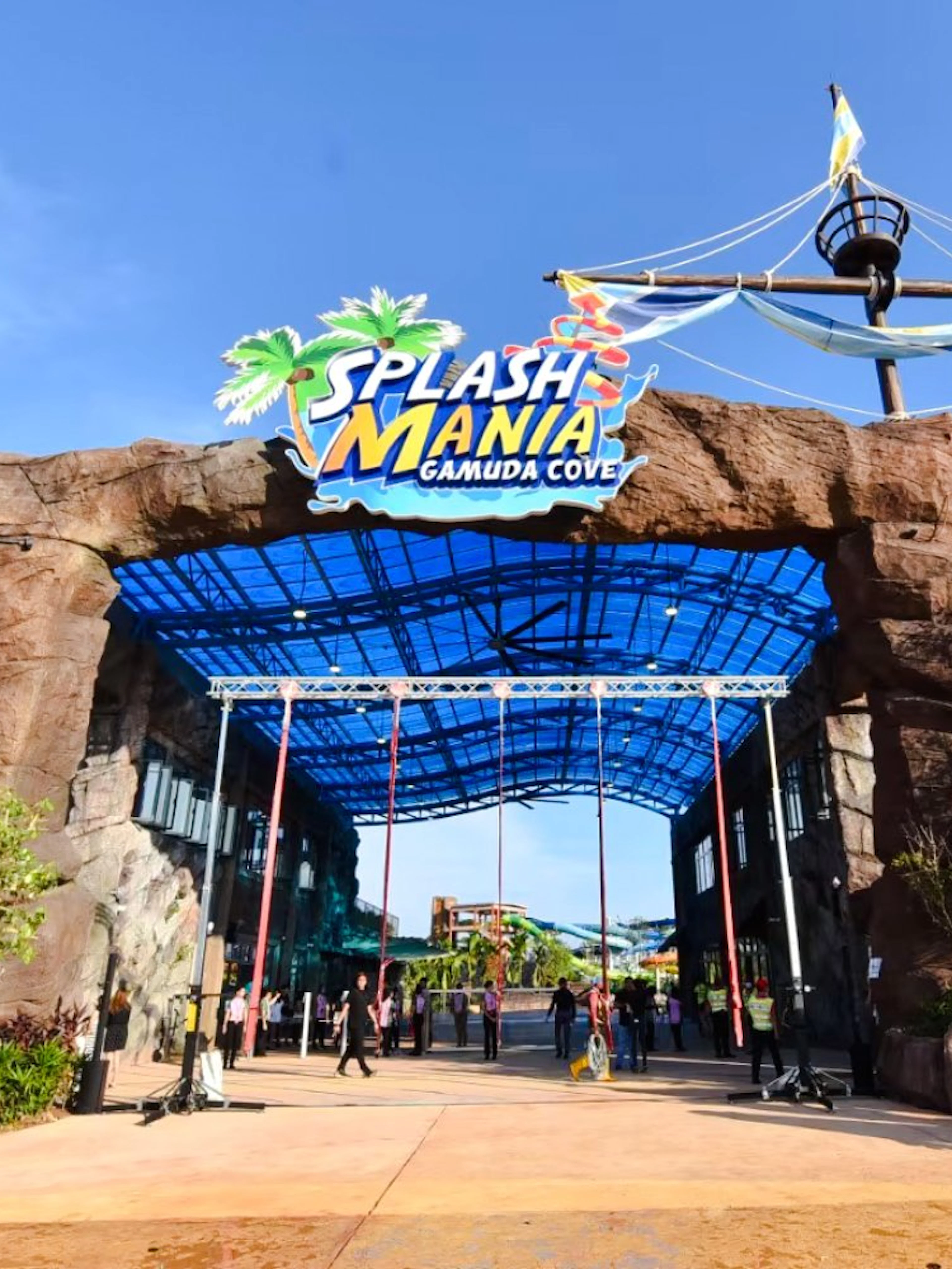 Entrance of SplashMania Waterpark with rock archway and colorful signage.