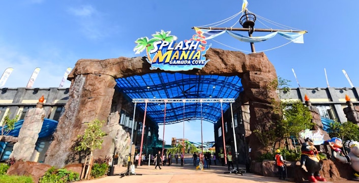Entrance of SplashMania Waterpark with rock archway and colorful signage.