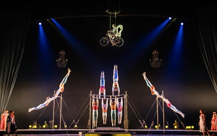 Acrobats performing on a suspended bicycle and parallel bars at Cirque du Soleil: Corteo.