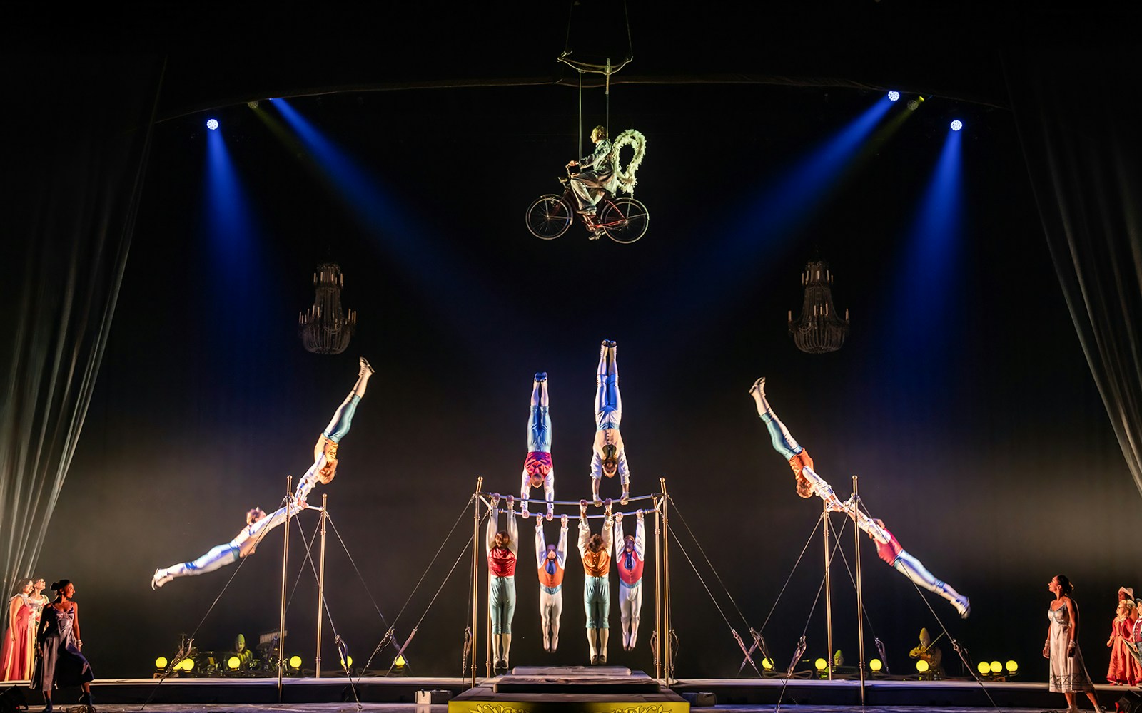 Acrobats performing on a suspended bicycle and parallel bars at Cirque du Soleil: Corteo.