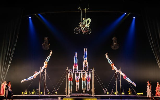 Acrobats performing on a suspended bicycle and parallel bars at Cirque du Soleil: Corteo.