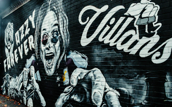 Graffiti of Ozzy Osbourne with "Ozzy Forever" text on a brick wall.