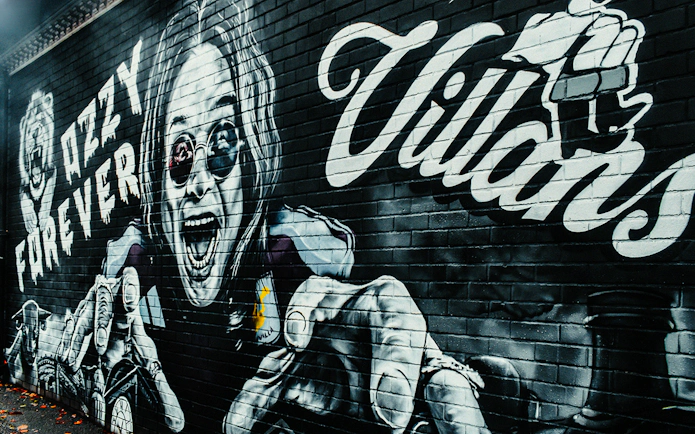 Graffiti of Ozzy Osbourne with "Ozzy Forever" text on a brick wall.