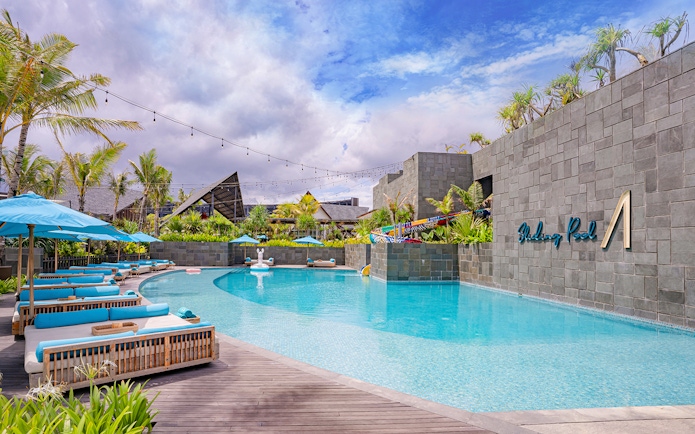 Atlas Beach Club poolside with lounge chairs and palm trees.
