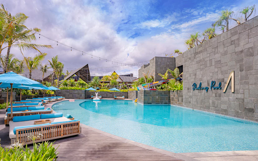 Atlas Beach Club poolside with lounge chairs and palm trees.