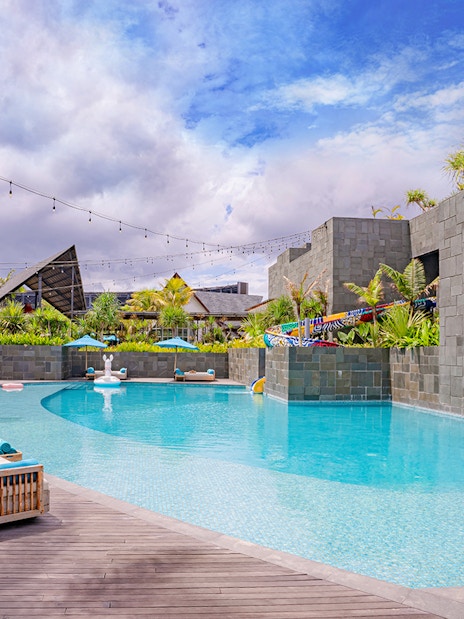 Atlas Beach Club poolside with lounge chairs and palm trees.