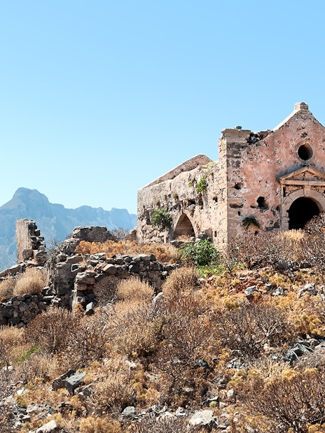 Ruined Venetian fortress church with mountain backdrop, Crete, Greece.