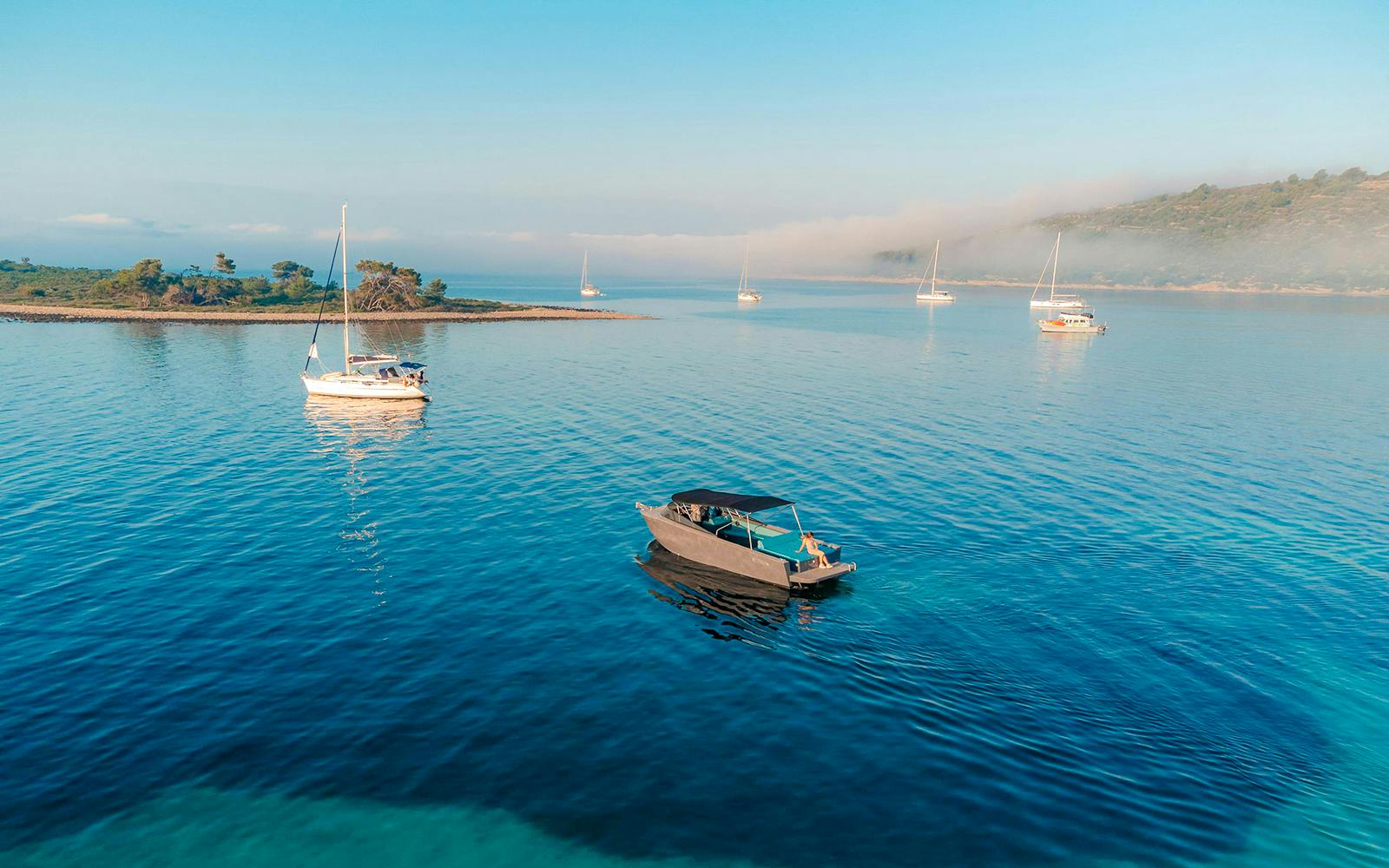 Luxury boat on Blue Lagoon tour with sailboats and scenic coastline.