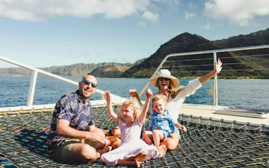 Family enjoying a sail on West Oahu Deluxe Whale Watch with mountains in the background.