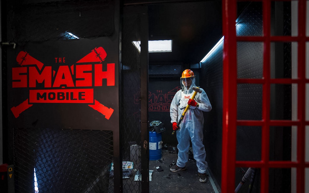 Tourist holding sledgehammer inside Smash room experience.