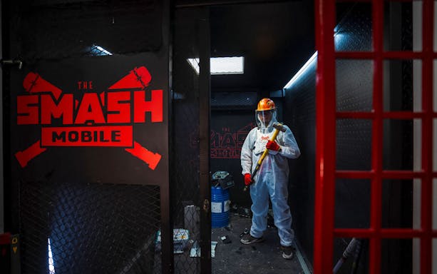 Tourist holding sledgehammer inside Smash room experience.