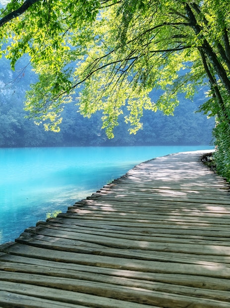 Footpath along turquoise lake in Plitvice Lakes National Park, Croatia.