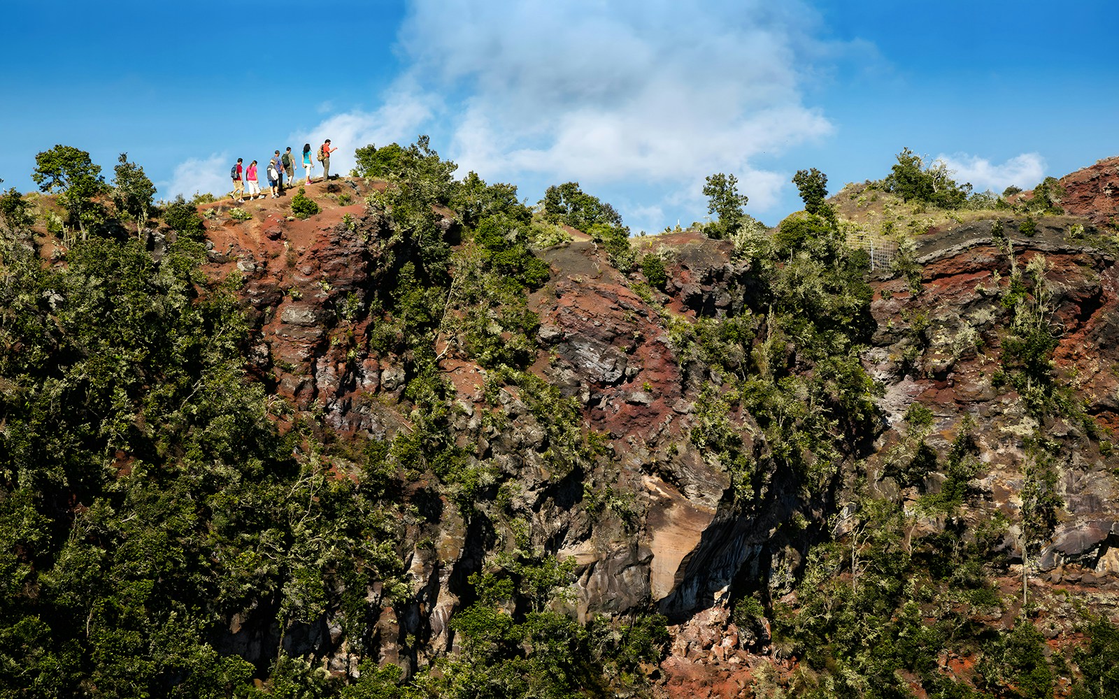 Guests hiking along a ridge on the Hidden Craters Hike, surrounded by lush greenery and rocky terrain.