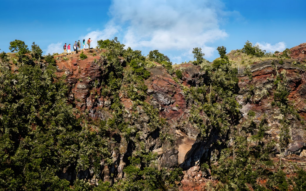 Guests hiking along a ridge on the Hidden Craters Hike, surrounded by lush greenery and rocky terrain.