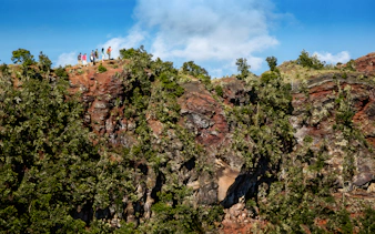 Guests hiking along a ridge on the Hidden Craters Hike, surrounded by lush greenery and rocky terrain.
