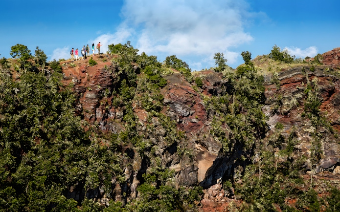Guests hiking along a ridge on the Hidden Craters Hike, surrounded by lush greenery and rocky terrain.