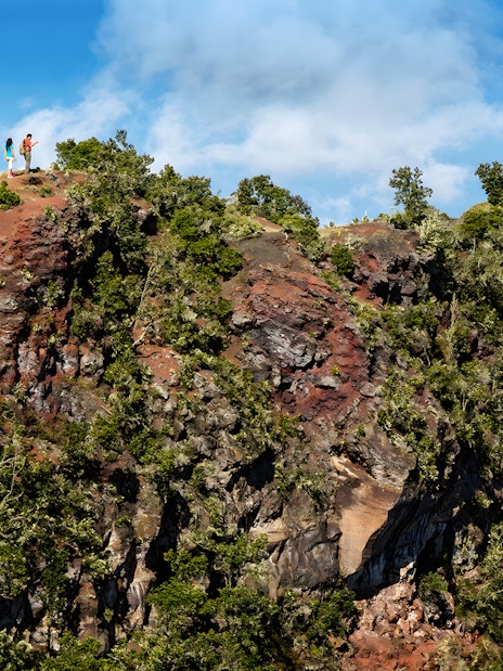Guests hiking along a ridge on the Hidden Craters Hike, surrounded by lush greenery and rocky terrain.