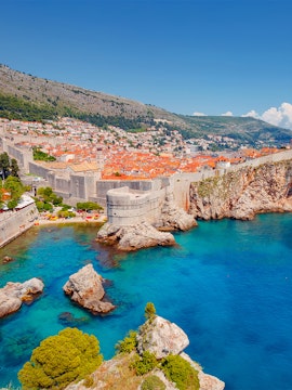 Dubrovnik city walls overlooking the Adriatic Sea with historic buildings and rocky coastline.