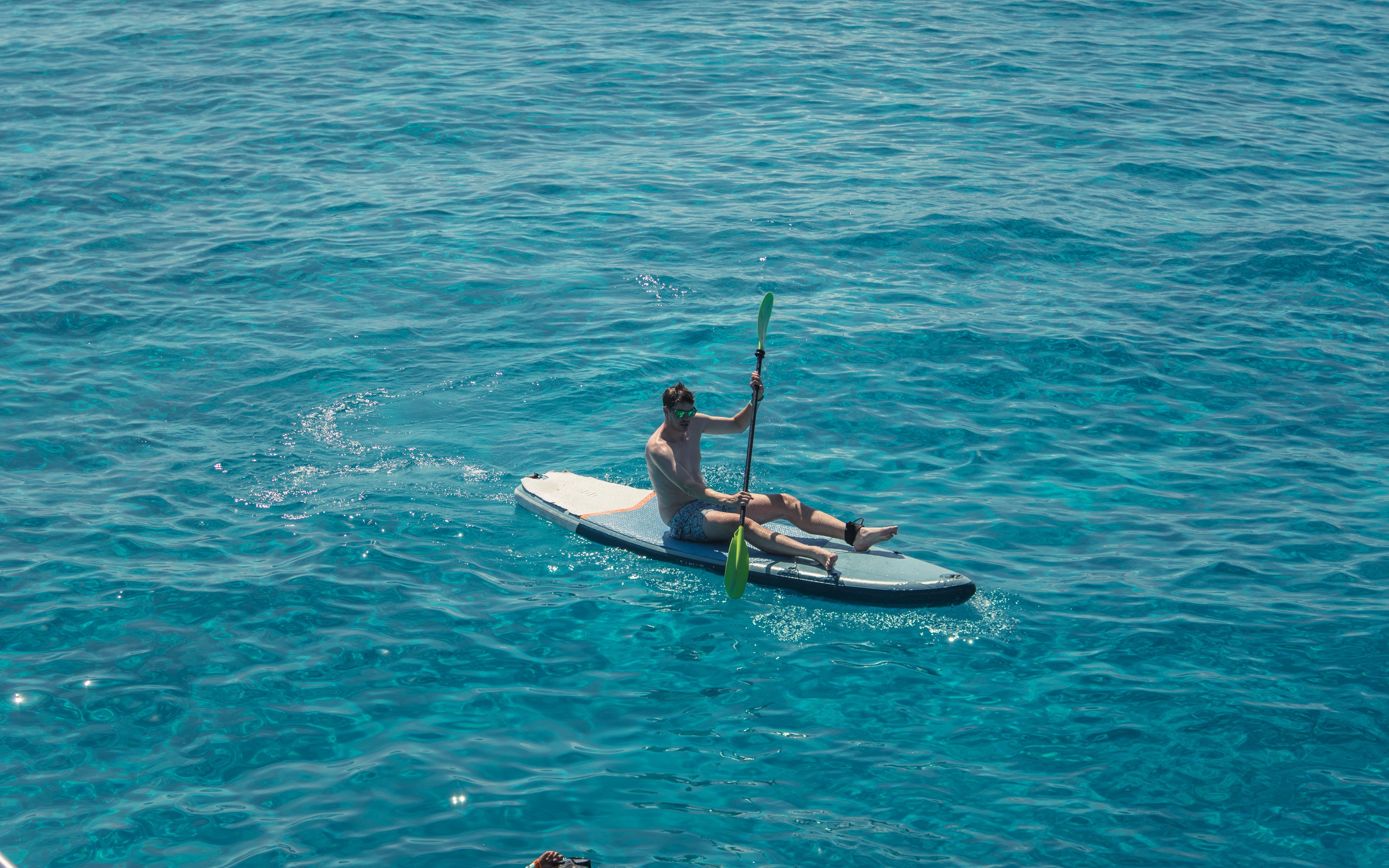 Tourist kayaking on Cala Bassa beach, Ibiza, Spain.
