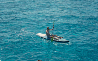 Tourist kayaking on Cala Bassa beach, Ibiza, Spain.
