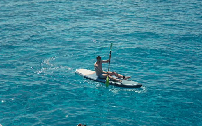 Tourist kayaking on Cala Bassa beach, Ibiza, Spain.