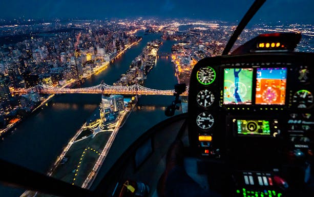 Helicopter view of NYC skyline and Queensboro Bridge at night.