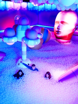 Visitors enjoying Bubble Planet installation with colorful lights and giant head sculpture.