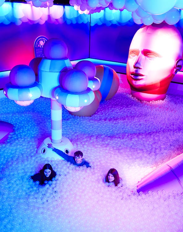 Visitors enjoying Bubble Planet installation with colorful lights and giant head sculpture.