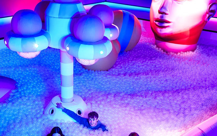 Visitors enjoying Bubble Planet installation with colorful lights and giant head sculpture.