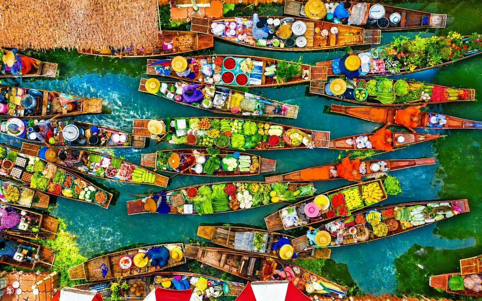 Aerial view of vibrant boats at a floating market with fresh produce in Thailand.