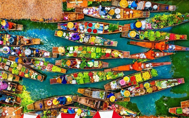 Aerial view of vibrant boats at a floating market with fresh produce in Thailand.