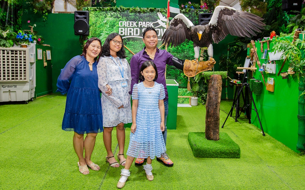 Tourists at Creek Park Bird Show posing with an eagle on a handler's glove.