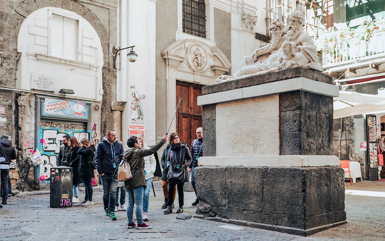 Group tour exploring historic statue in Naples street.