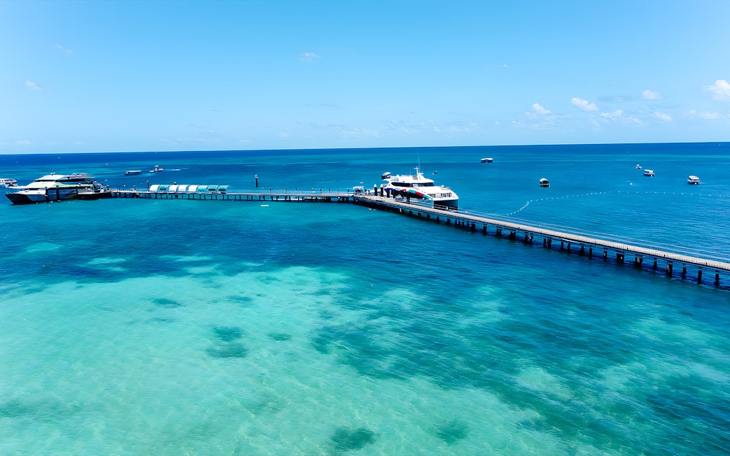 Docked boat at Green Island pier, Cairns, with clear turquoise waters and distant boats.